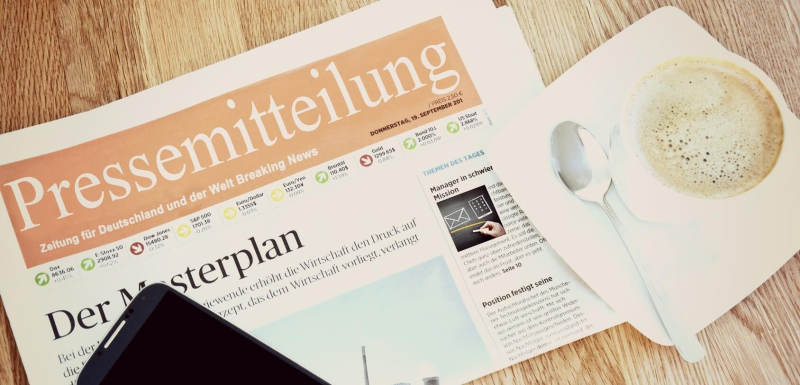 Zeitung, Handy und Tasse auf einem Holzuntergrund