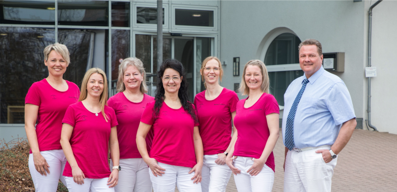 Team steht vor einem Gebäude und lächelt