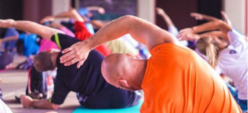 Präventionskurs Mehrere Menschen sieht man von hinten, die auf Matten eine Sportübung ausführen