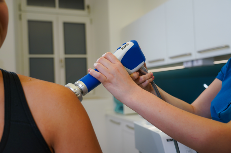 Arzt führt radiale Stoßwellentherapie mithilfe eines Applikator durch