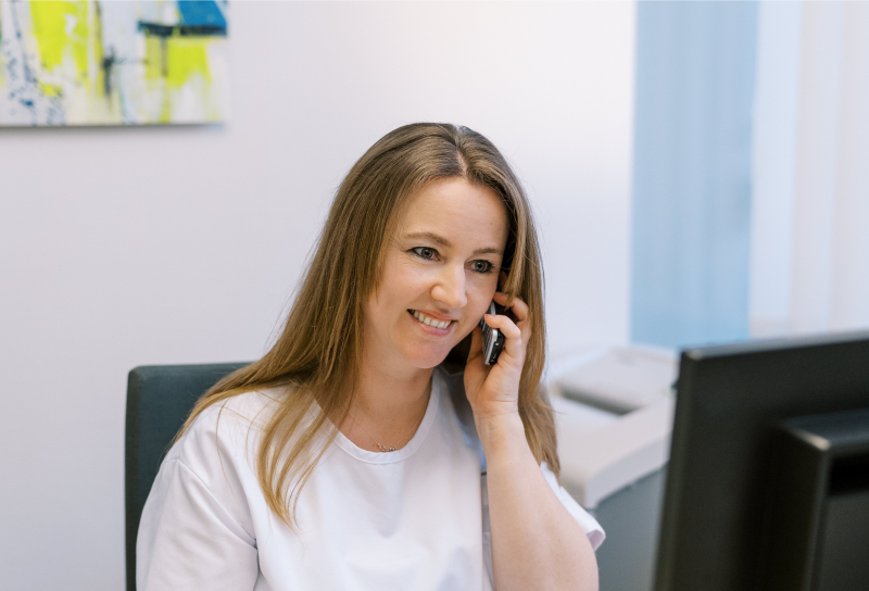 Frau sitzt hinter Rezeption am Telefon