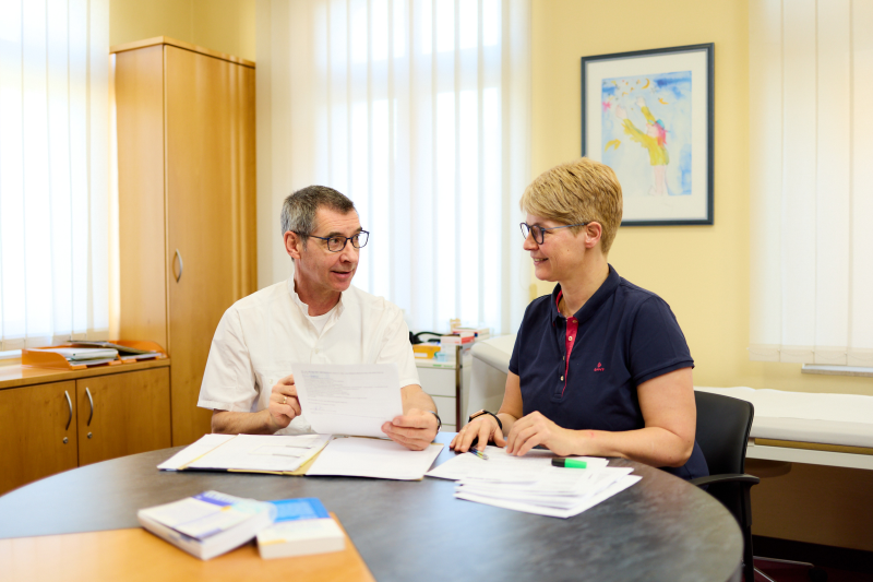 Ärzte im Gespräch | MVZ Gera Zwei Ärzt*innen sitzen zusammen und besprechen Unterlagen auf dem Tisch
