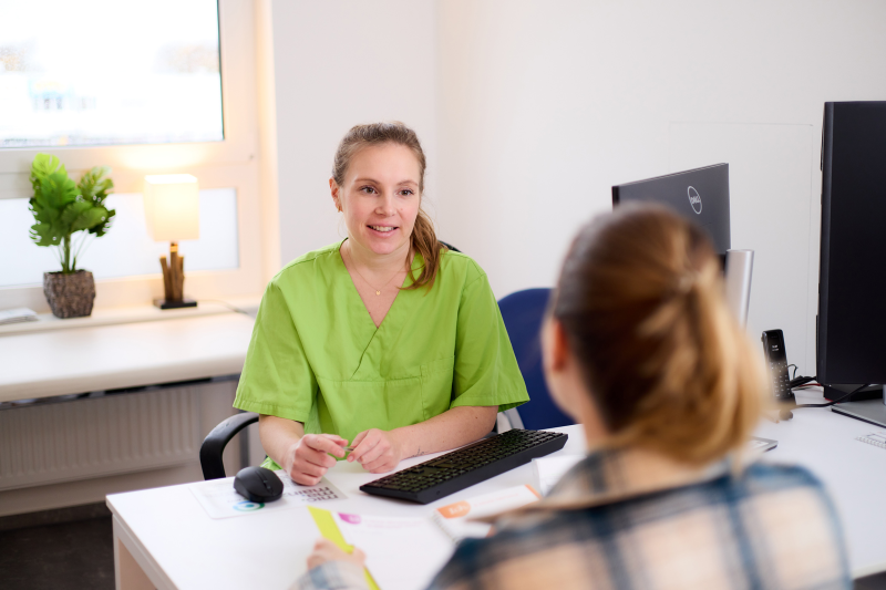 Ärztin bespricht mit Patient am Schreibtisch