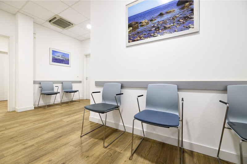 Wartebereich mit grauen Stühlen und Bildern an den Wänden