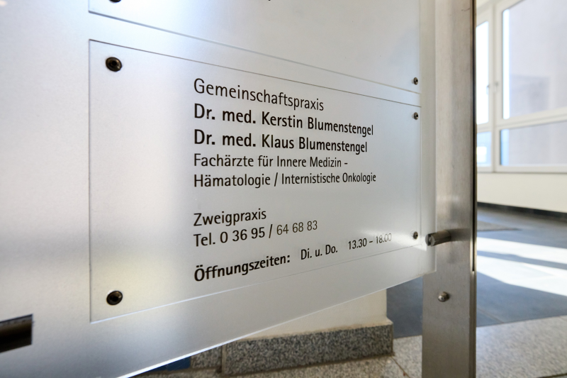 Praxisschild mit Ärzt:nnen, Telefonnummer und Öffnungszeiten