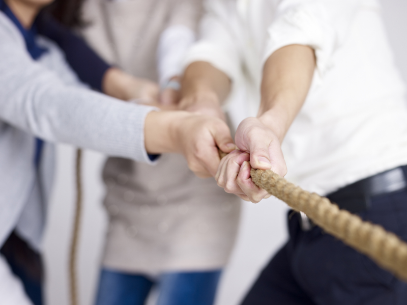 Drei Menschen ziehen gemeinsam an einem Seil