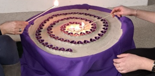 Anlass-Spende rote Teelichter in Herzform sind in Spiralform aufgereiht und werden von Personen angezündet