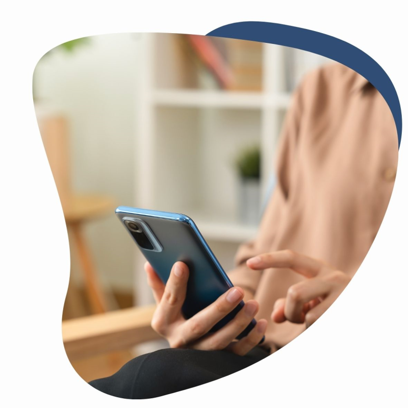 Patient in einem orangenen Pullover hält ein Handy in der Hand 