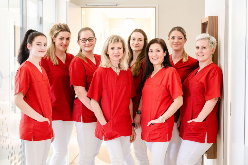 Team von OnkoMedeor Acht Frauen in orangenen Kitteln stehen nebeneinander und sind Mitarbeiterinnen von OnkoMedeor