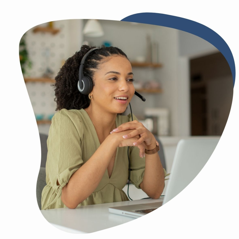 Frau mit einem Headset auf dem Kopf und einem Laptop vor sich lächelt