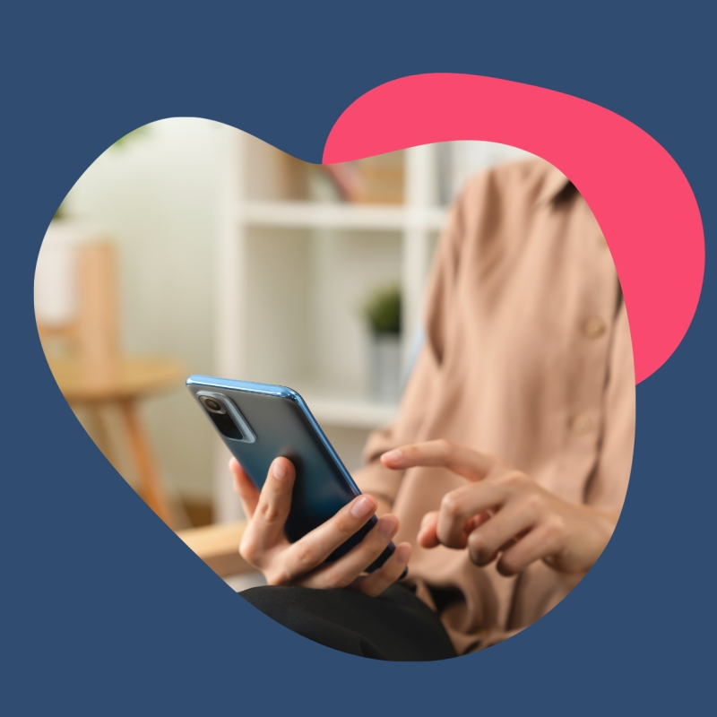 Person in einem hellen Oberteil hat ein Handy in der Hand und tippt etwas auf dem Display