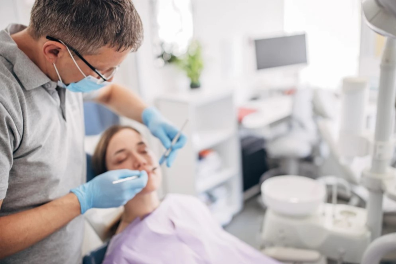 Ein Mann, der Zahnarzt ist, behandelt eine Patientin