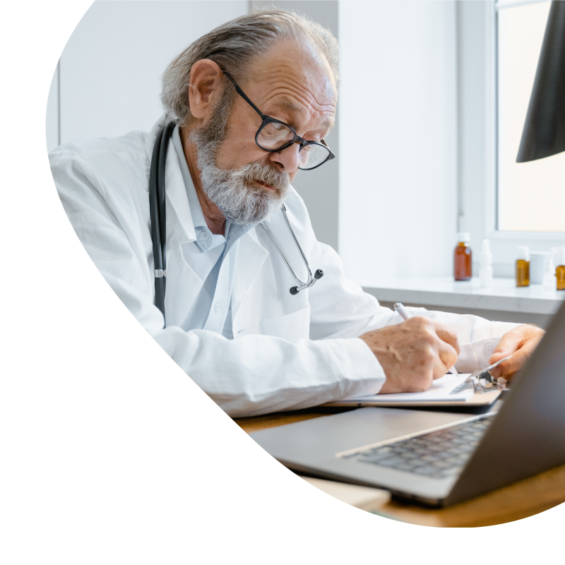 Ein älterer Arzt schaut in einen PC