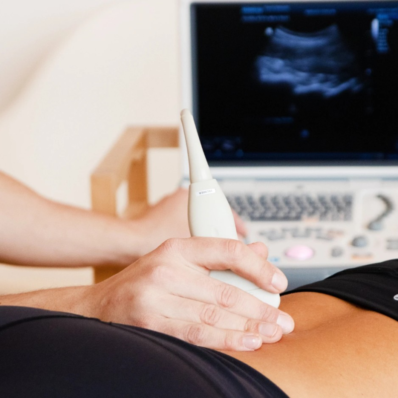 Ultraschall Physiotherapeut führt Ultraschalluntersuchung am Bauch einer Patientin durch