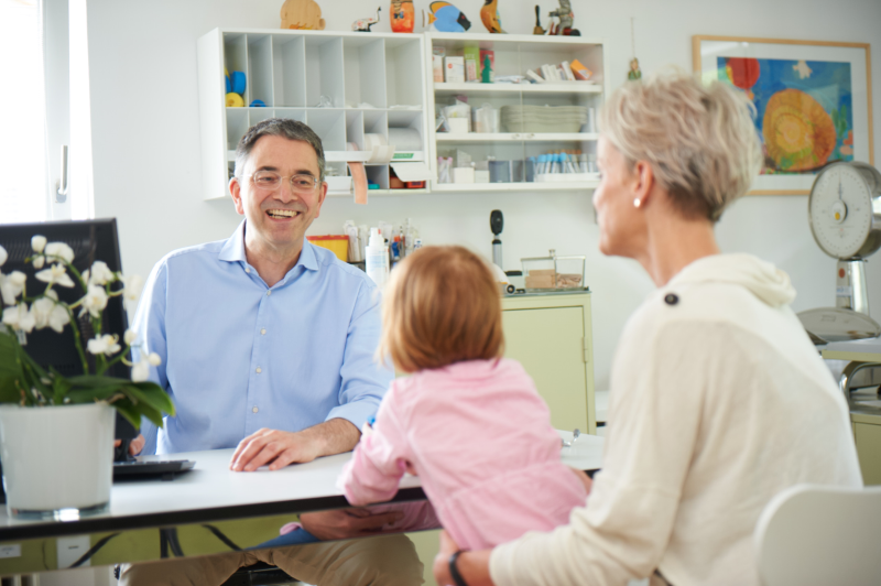 Arzt im Besprechungsraum mit Mutter und Kind Arzt im Besprechungsraum mit Mutter und Kind